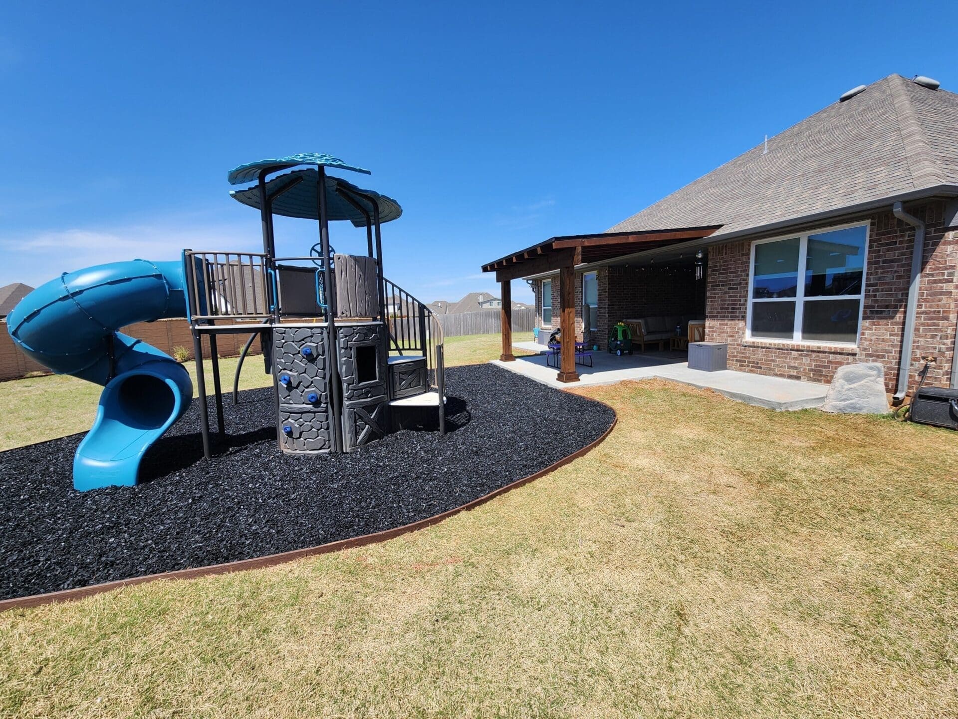 Backyard playground landscape installation with decorative rock in Oklahoma