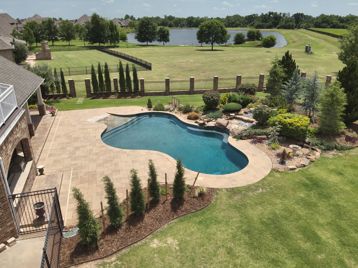 Backyard pool landscape installation with privacy trees in Oklahoma