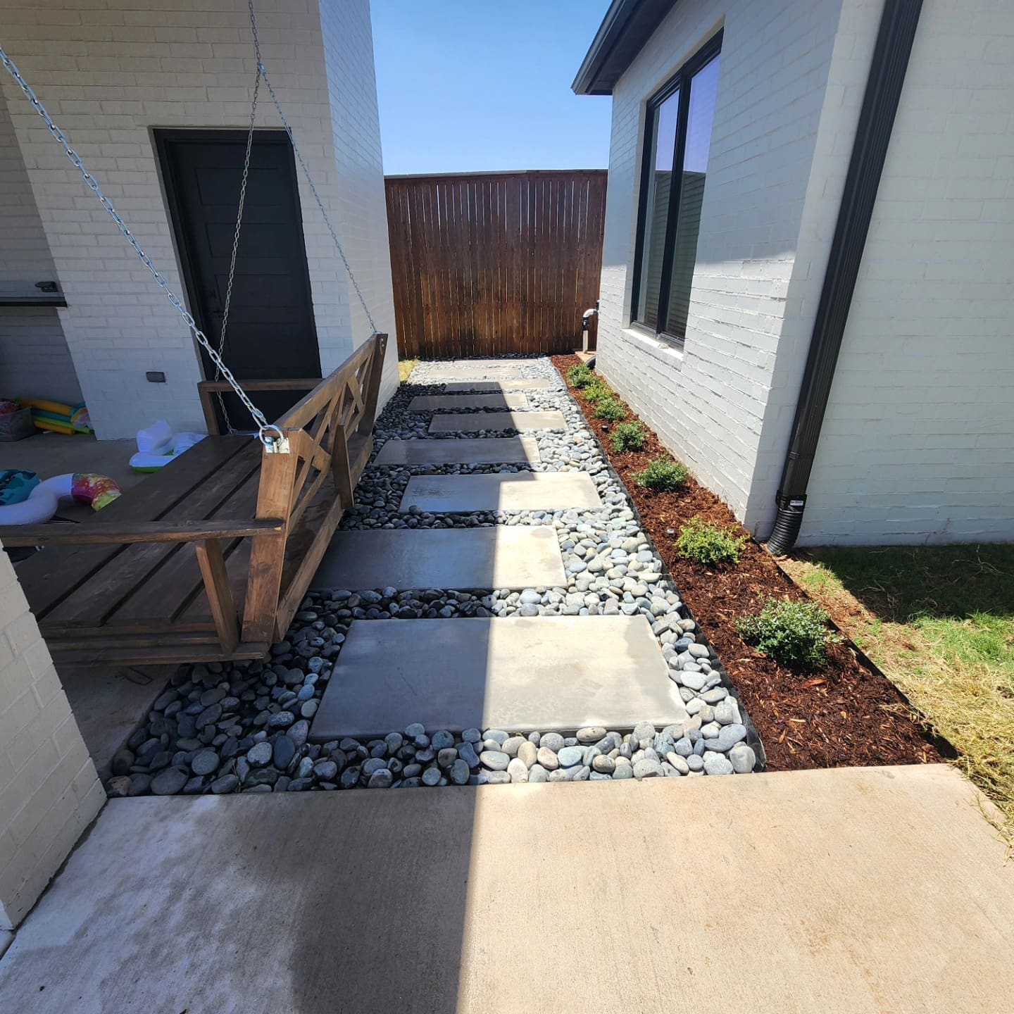 Decorative rock drainage walkway installation beside house in Oklahoma