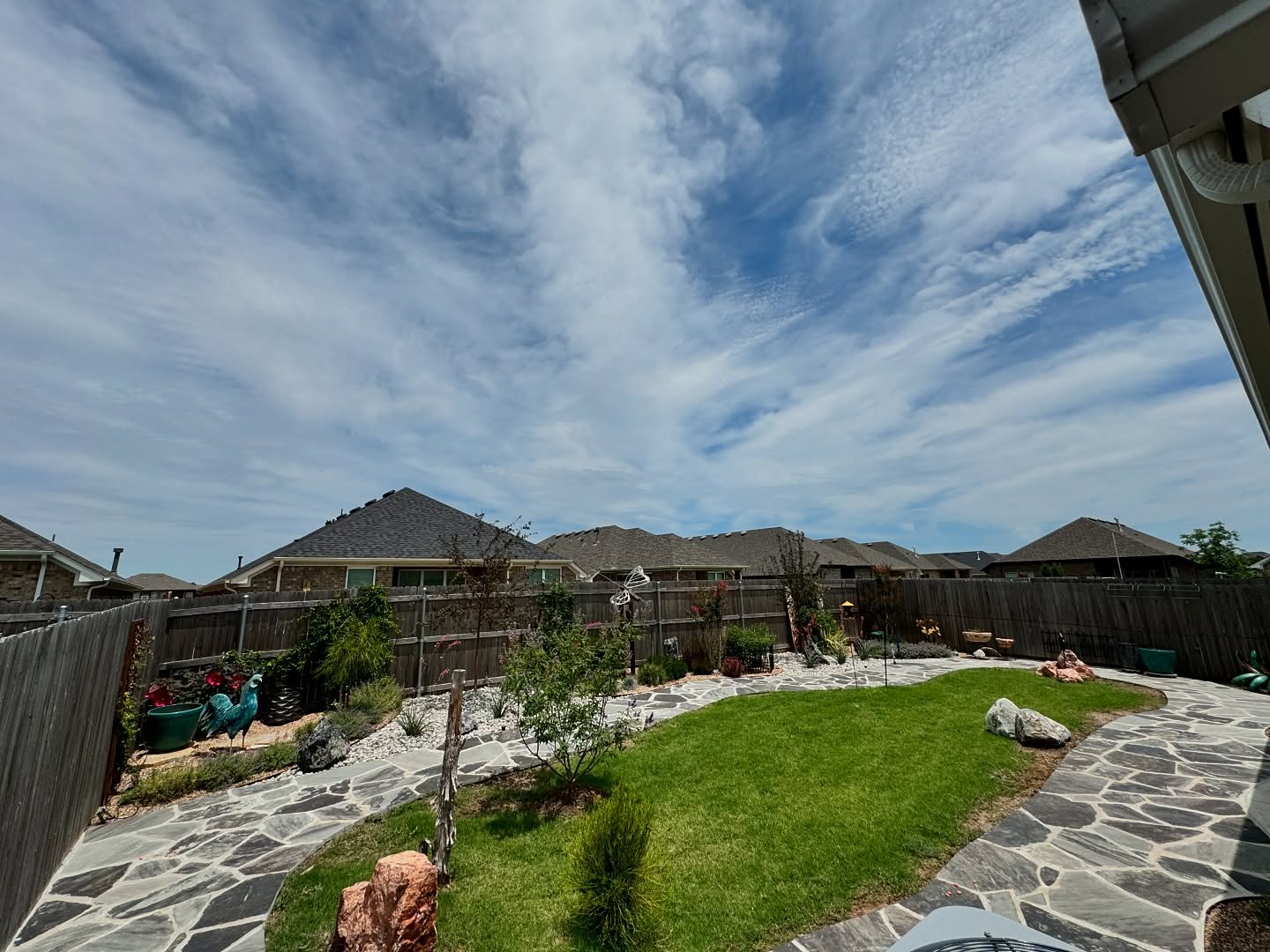 Backyard landscape installation with curved lawn and garden beds in Oklahoma
